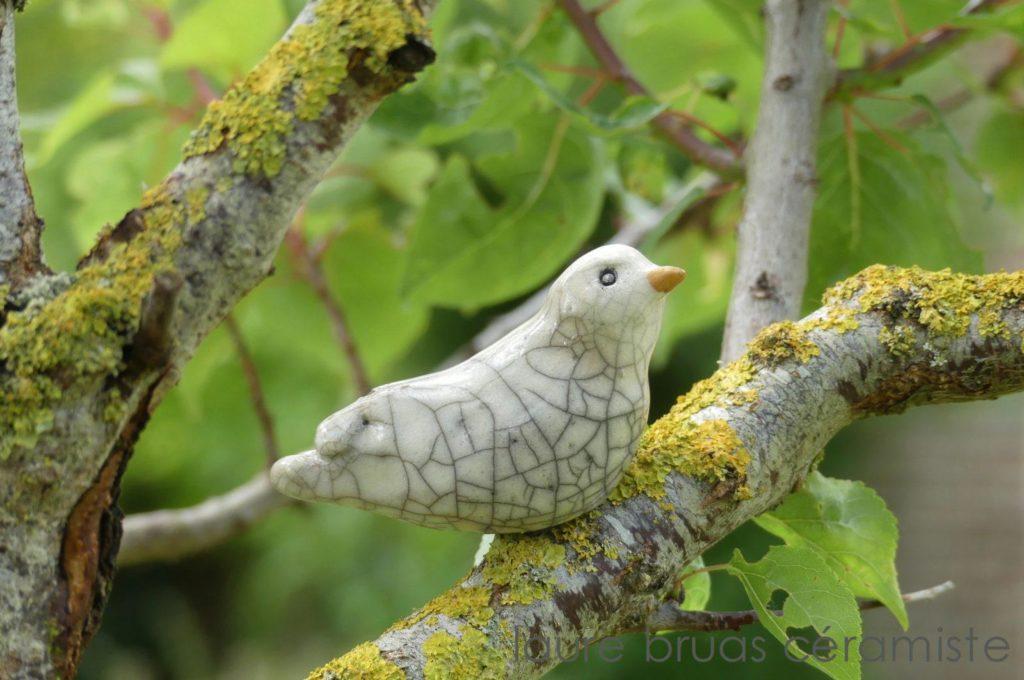 Colombe blanche craquelée en céramique raku posée sur une branche d'arbre