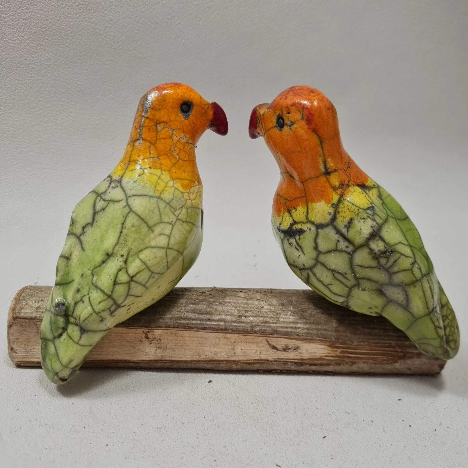 Inséparables - le couple d'oiseaux en raku sur une branche