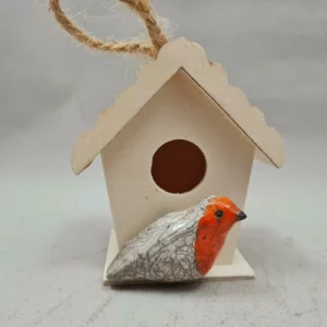 Mini rouge-gorge en céramique Raku devant son nichoir en bois réalisé à la main